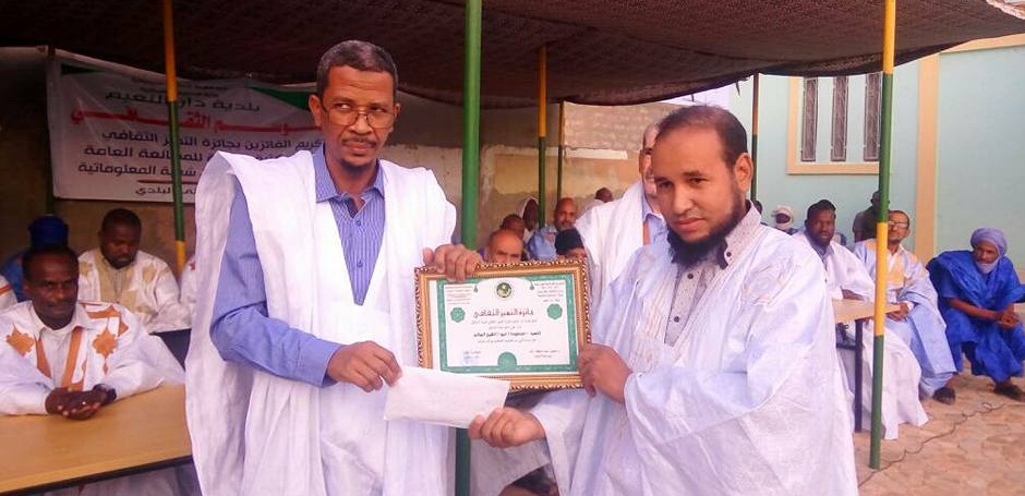 العمدة وهو يسلم الجائزة للفائز الأول بالمسابقة الثقافية الأخيرة